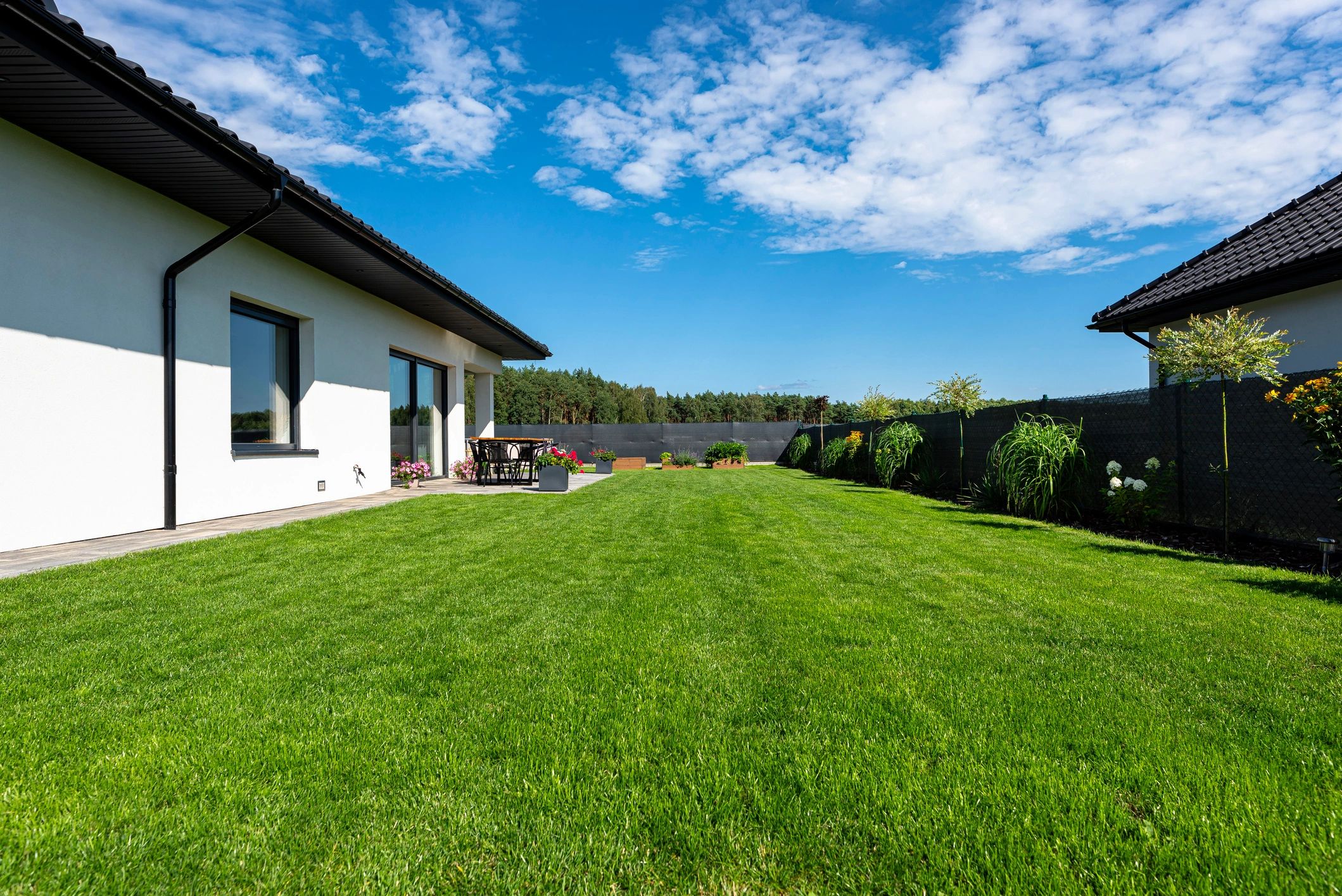 Well-maintained backyard with stone patio and green lawn